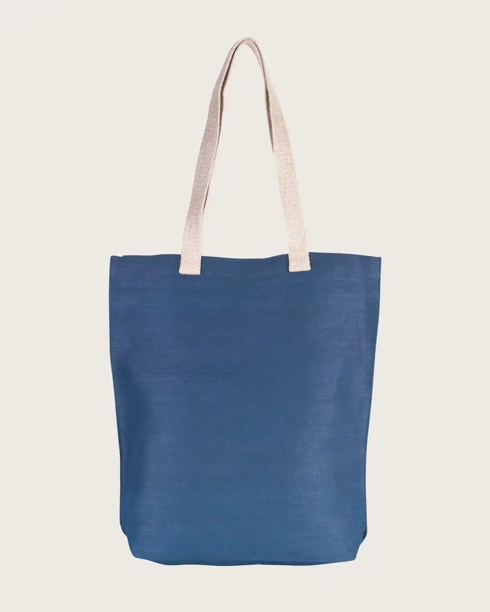 Blaue nachhaltige Stofftasche mit beigen Henkeln auf hellem Hintergrund