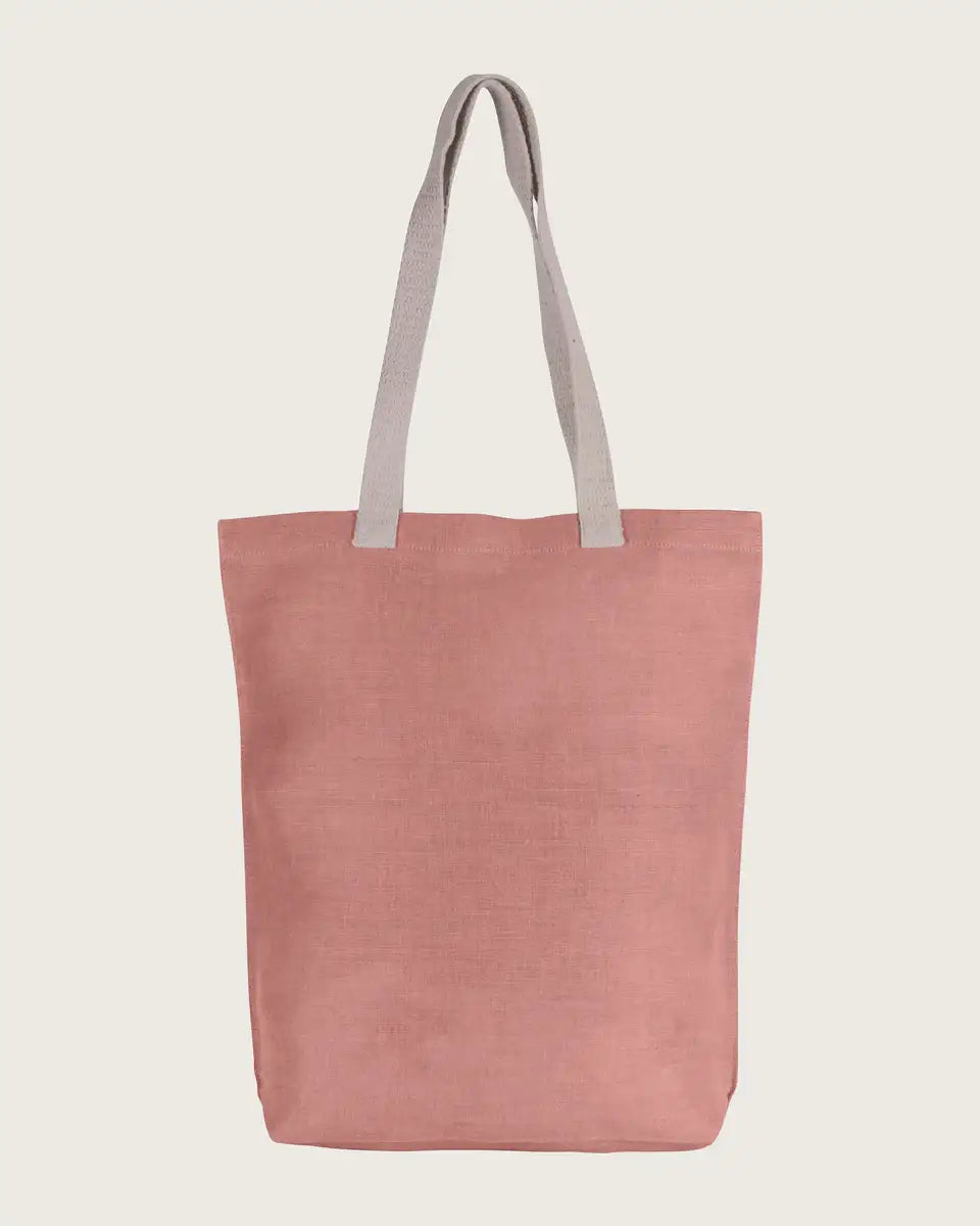 Nachhaltige rosafarbene Stofftasche mit langen hellen Henkeln auf hellem Hintergrund