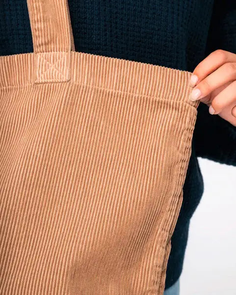 Große, umweltfreundliche Cordtasche in Beige, Nahaufnahme mit Hand am Henkel.