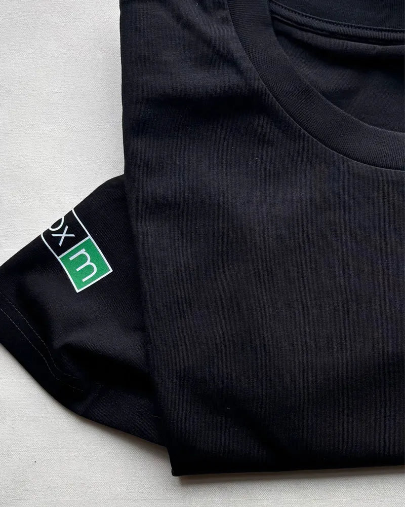 Schwarzes Unisex T-Shirt mit grün-weißem Aufdruck am Ärmel auf weißem Hintergrund