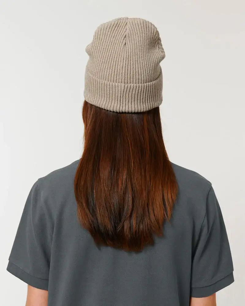 Person mit langen braunen Haaren trägt eine beige gestrickte Wollmütze, Rückansicht.