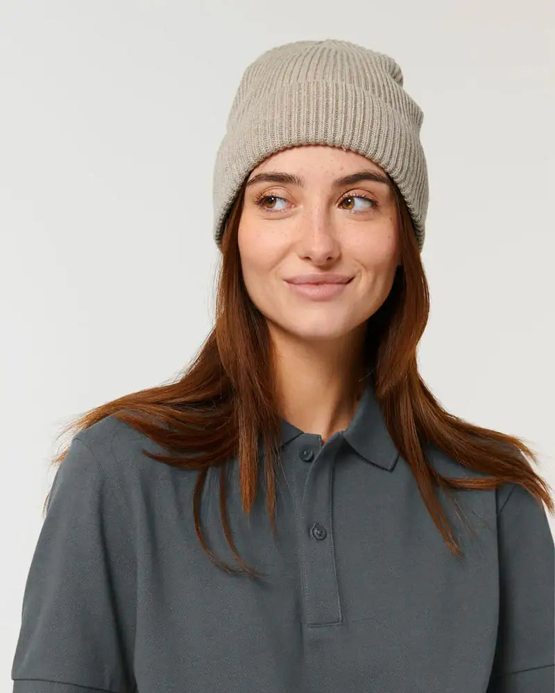 Frau mit beigefarbener Wollmütze und grauem Poloshirt, Fischer-Beanie Stil