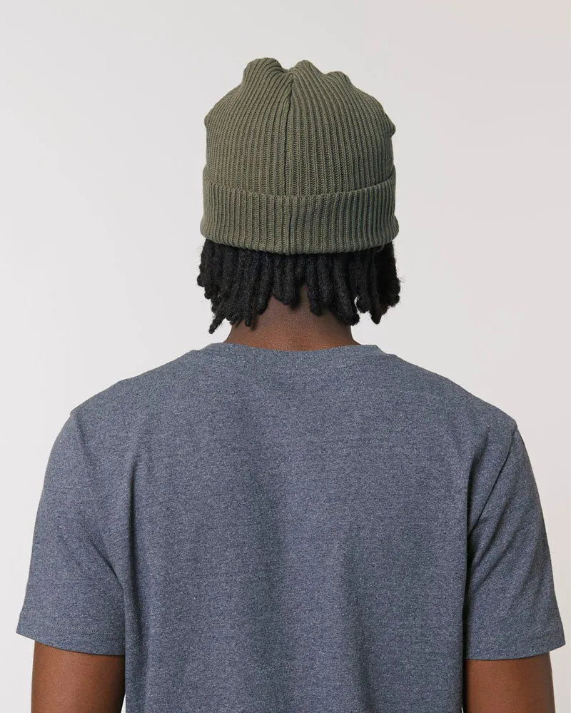 Person mit olivgrüner Fisherman-Beanie Wollmütze und grauem T-Shirt, Rückansicht