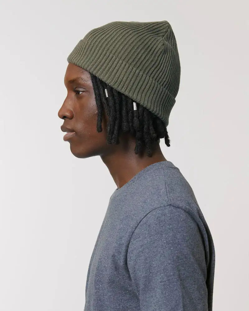 Seitliches Portrait eines Mannes mit olivgrüner Strickmütze und grauem Shirt