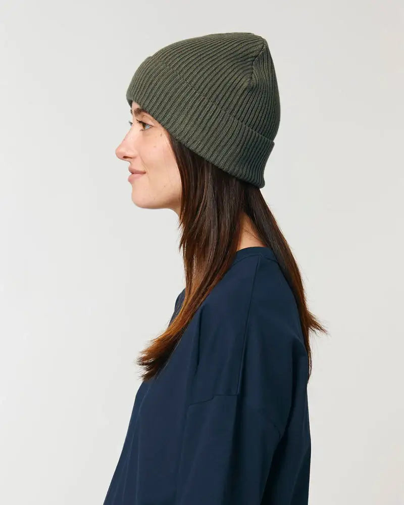 Frau mit olivgrüner Fisherman Beanie Wollmütze und dunkelblauem Oberteil im Profil
