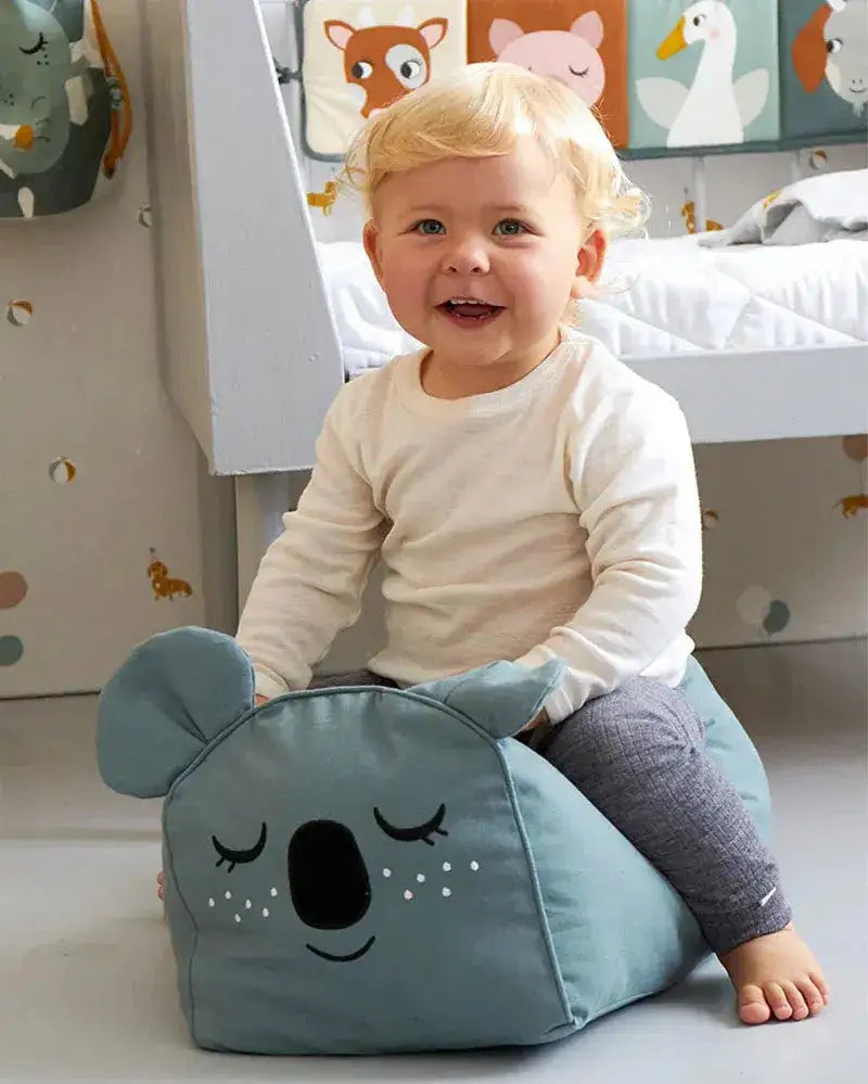Kleinkind sitzt auf einem Koala-Sitzkissen im Kinderzimmer, nachhaltige Kinderzimmer-Deko
