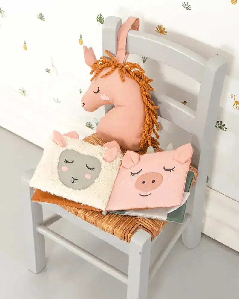 Stofftiere und nachhaltige Babybücher mit Tiermotiven auf Kinderstuhl im Kinderzimmer