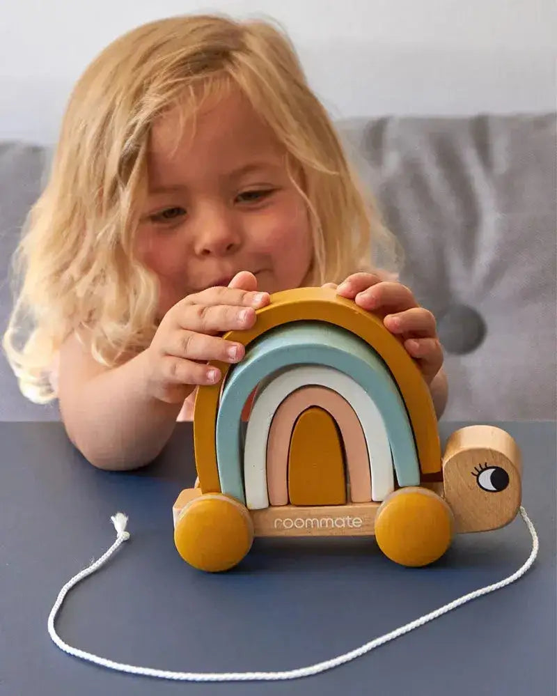 Kind spielt mit nachhaltigem Holzspielzeug Schildkröte mit Regenbogen und Zugband