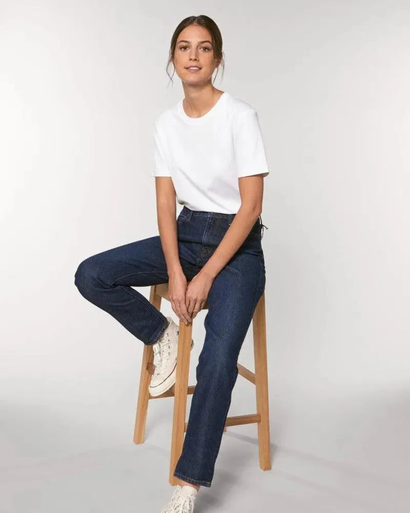 Frau in weißem unisex Bio-baumwollt-shirt auf einem Hocker